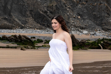 Fototapeta na wymiar young woman in white dress walking on the beach
