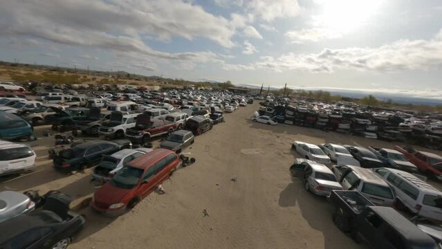 FPV aerials fast flying over and through a vast automotive junkyard in the California desert near Lancaster