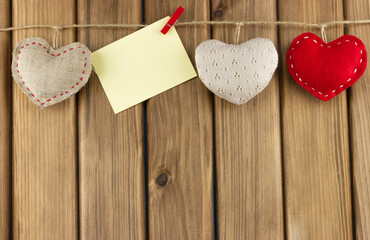 Blank card on a rope with cute hearts on a wooden background.