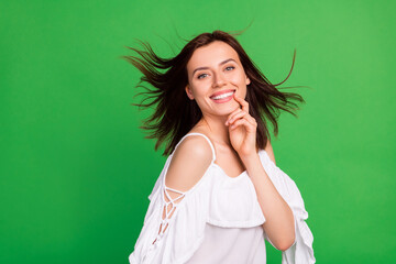 Fototapeta Photo of positive adorable lady arm finger touch chin beaming smile isolated on green color background obraz