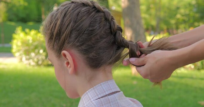 Mother making hairstyle french braid her daughter