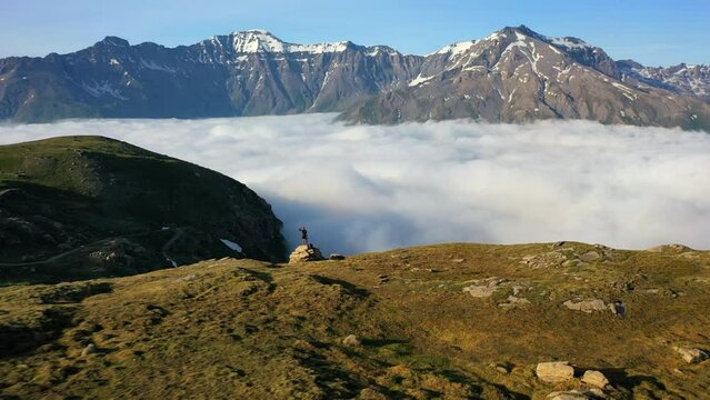 Aerial Forward Shot Of Male Tourist Standing On Mountain By Clouds During Vacation - Val-Cenis, France