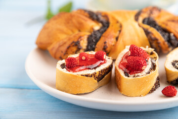 Sweet bun with strawberry jam on a blue wooden background, side view, selective focus.