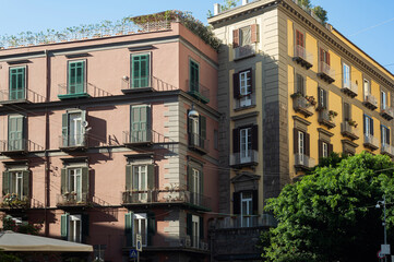 Fototapeta na wymiar Residential areas of Naples, Italy. Beautiful various balconies on the facades of beautiful houses. Italian architecture. Classic shuttered windows and Balconies in a classic red house.