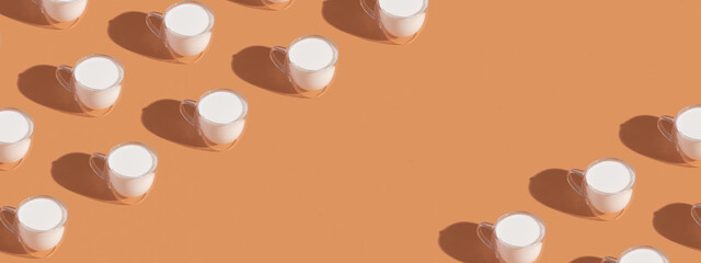 Banner with milk in a glass pattern on orange colored background, dairy diet concept with copy space