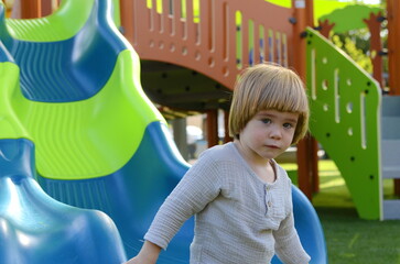 Fototapeta na wymiar Cute boy on the playground. Concept: Kindergarten advertisement, children's vacation, preschool education, travelling, family resort, water park