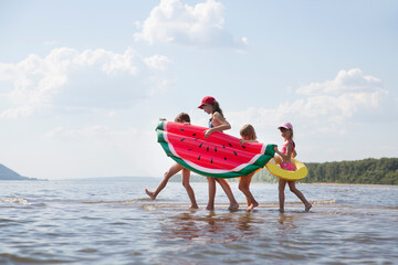 Summer lifestyle a group of children of different ages in swimwear with air mattress looks like...