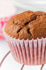 Chocolate muffin in paper baking cup on metal cooling rack close-up.
