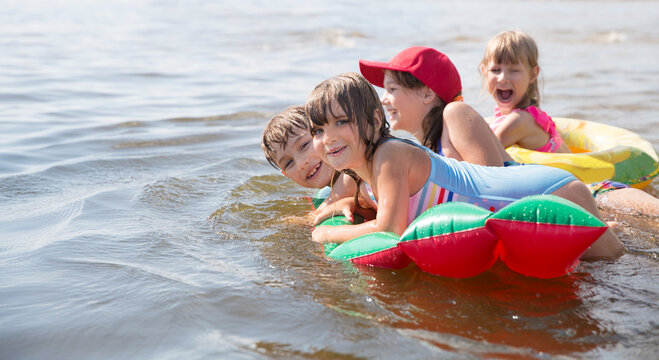 Summer lifestyle a group of children of different ages in swimwear float on air mattress looks like watermelon. Enjoying the little things. spends time in nature in summer