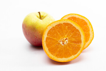 połówki pomarańczy oraz jabłko na białym tle