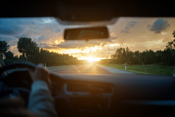 Driving car in summertime on the sunset.