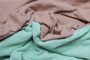 Light brown and green muslin, soft cotton fabric crumpled with folds close-up, with empty space for text, copy space, concept  eco-friendly clothing and textiles, eco-friendly clothing, soft washing 