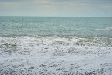 Small seaside waves near the coastline in the sand on a warm summer day