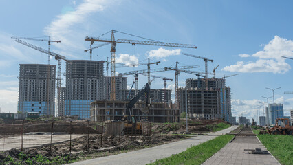 Construction of a multi-story residential buildings. A lot of construction equipment, cranes work. Construction site.