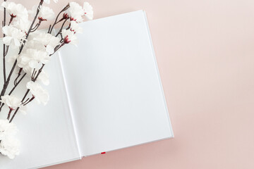 White book mockup on a pastel pink background with white and pink cherry blossom. Education, reading. Brochure, magazine, book or catalog mock up isolated. Copy space.
