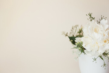 delicate white bouquet of flowers on milky background with copy space. mockup for wedding invitation or congratulations on women's day