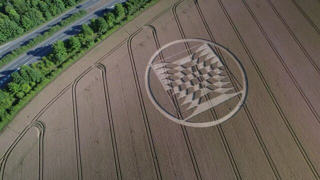 Aerial video of crop circles in a field of yellow grain in the UK's Micheldever Station are captured by drone with nearby traffic