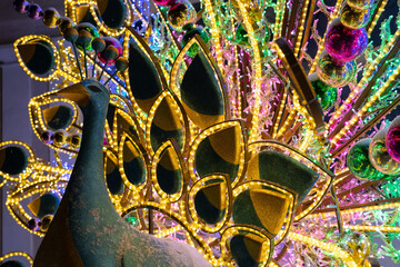 Large Christmas luminous decoration in the form of a peacock in winter. Beautiful illuminated Christmas sculpture on street.