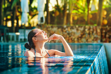 Attractive young woman relaxing in spa pool during summer vacation.
