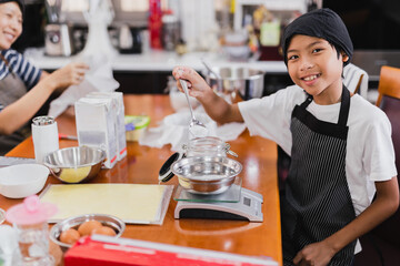 Young boy and his mum preparing ingredient for baking cake in kitchen.