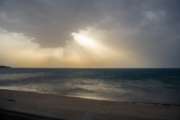 sunset on the beach with sun shining through the clouds