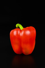 Deep red bell pepper on black background.
