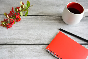red notepad with cup of hot tea on the gray background, close-up