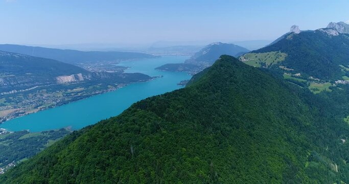 Aerial shot of forest covered mountains and turquoise water lake