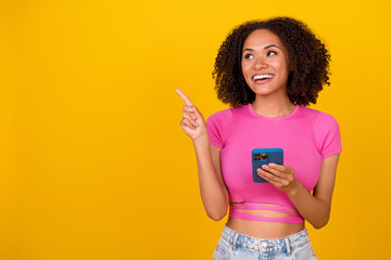 Photo of impressed brunette millennial lady hold telephone look up wear pink top isolated on bright orange color background