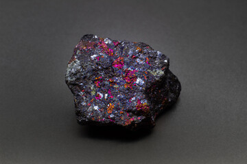 Focused macro raw colourful golden, pink and purple chalcopyrite isolated on gray background...