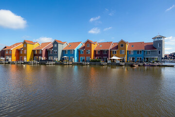 Fototapeta na wymiar Amazing panorama multi color buildings on water side, Dutch style modern houses with colorful on harbor port with blue sky background, Reitdiephaven, Groningen is a city in the northern Netherlands