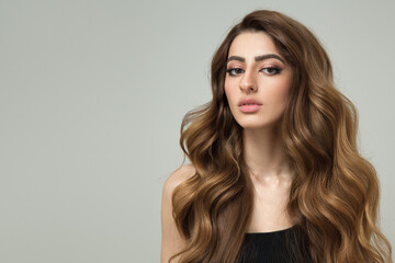 Naklejka premium Portrait of a beautiful brunette woman with long wavy hair. Copycpase
