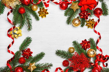 New Year greeting card. Christmas tree branches with red and yellow balls on white wooden background close-up and copy space.