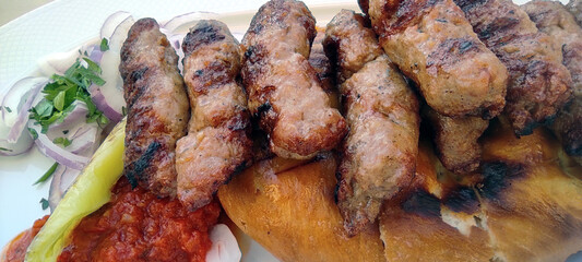 Large fried pieces of juicy meat on bread with tamat seasoning with red onion rings and a slice of green pepper