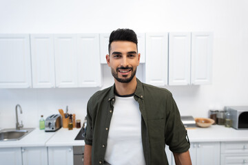 Smiling arabian man looking at camera in kitchen