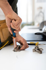 Cropped view of man with screwdriver fixing hinge of cupboard