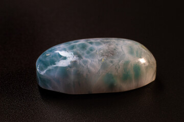 Larimar cabochon on black background macro. Close up picture of oval shaped stone