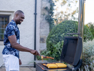 Man grilling corn and meat on barbecue grill © Cultura Creative