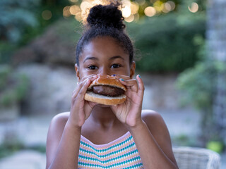 Portrait of girl (8-9) eating hamburger