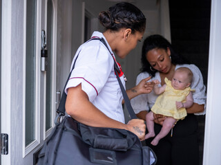 Nurse visiting woman with baby girl (2-5�months)�at their home