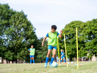 Children (8-9) dressed in uniforms practicing on soccer field
