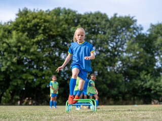 Children (8-9) dressed in uniforms practicing on soccer field © Cultura Creative
