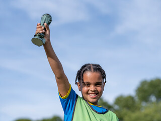 Boy (8-9) dressed in soccer uniform holding prize © Cultura Creative