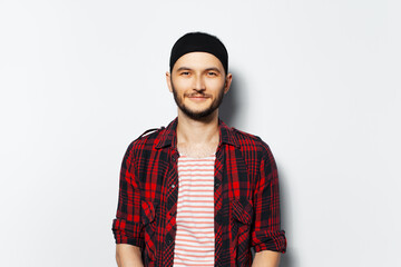 Studio portrait of young cute guy, wearing red plaid shirt and black headband.