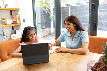 UK, London, Smiling mother and daughter using digital tablet at home