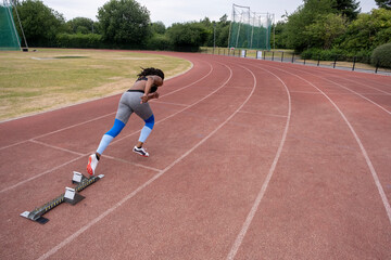 Fototapeta premium Rear view of athletic�woman running on track