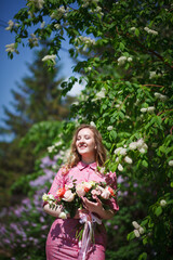 Young happy blonde woman in a pink dress with a large bouquet of flowers walks around the old European city and enjoys life on a summer day, beautiful portraits with a huge bouquet of flowers.