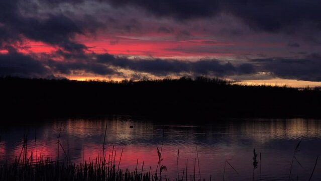 Sunset over water with reeds in tranquil place for meditation and relaxation UK 4K