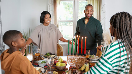 Family with children (8-9, 12-13) holding hands over Kwanzaa meal