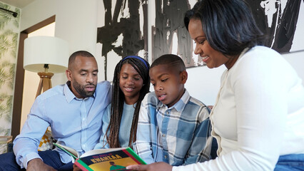 Family with children (8-9, 12-13) reading book about Kwanzaa at home